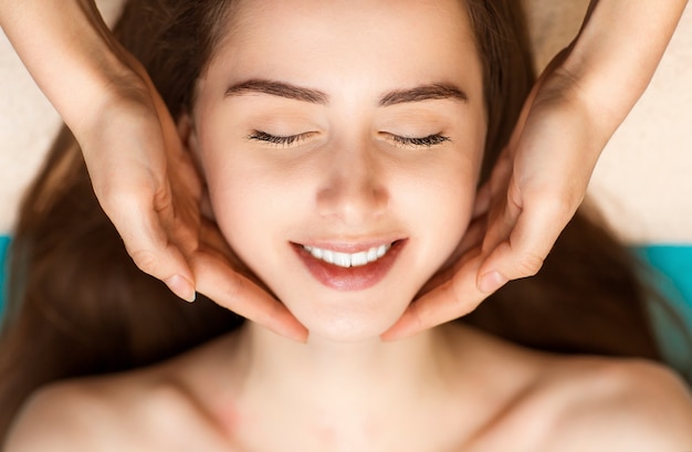 Face building facial massage and rejuvenating exercises for woman face in beauty spa
