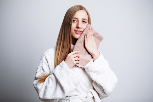 Face care, beautiful woman wipes her face with a towel after taking a shower.