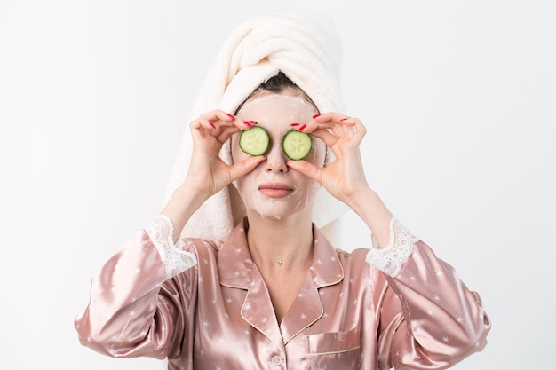 Face care and beauty treatments Woman with a sheet moisturizing cucumber mask on her face isolated on white background