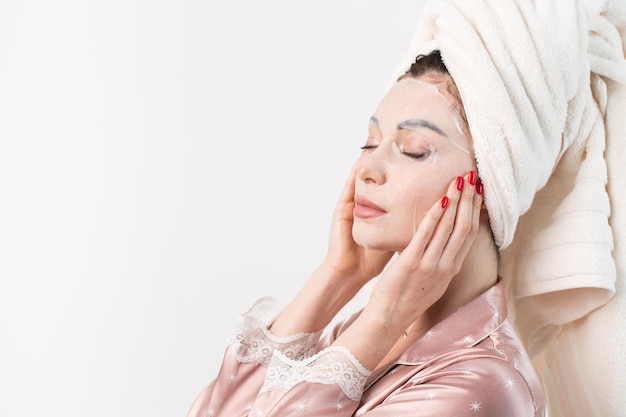 Face care and beauty treatments Woman with a sheet moisturizing mask on her face isolated on white background