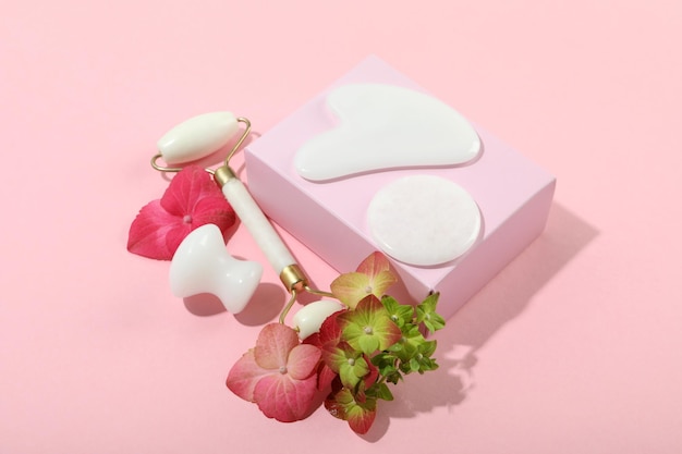 Face care concept with gua sha kit on pink background