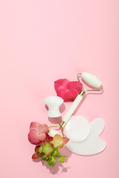 Face care concept with gua sha kit on pink background