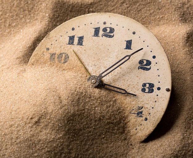 Face of clock in sand