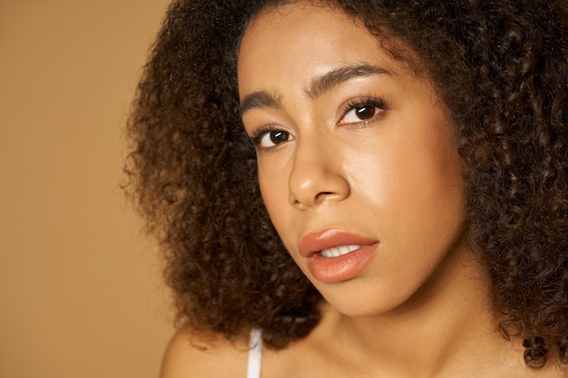 Face closeup of beautiful mixed race young woman with curly hair looking at camera  