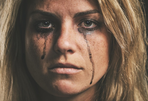 Face crying and domestic violence with a woman victim of abuse in studio with makeup closeup Sad fear and pain with a scared female feeling angry or emotional with grief tears and problems