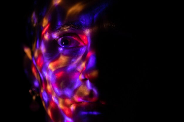 a face in the dark covered with bright colored spots from a bright lamp colored glare from the lamp