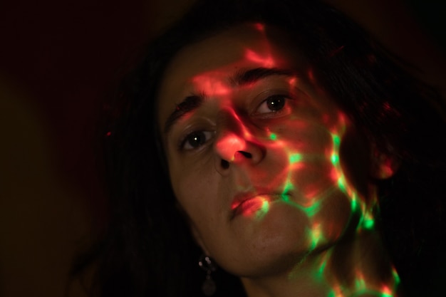 a face in the dark covered with bright colored spots from a bright lamp colored glare from the lamp