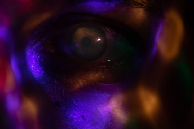 a face in the dark covered with bright colored spots from a bright lamp colored glare from the lamp