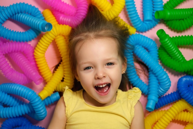 Face of an emotional screaming funny child surrounded by a large number of popular pop tubes toy