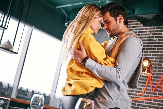 Face to face beautiful young couple are hugging in a restaurant