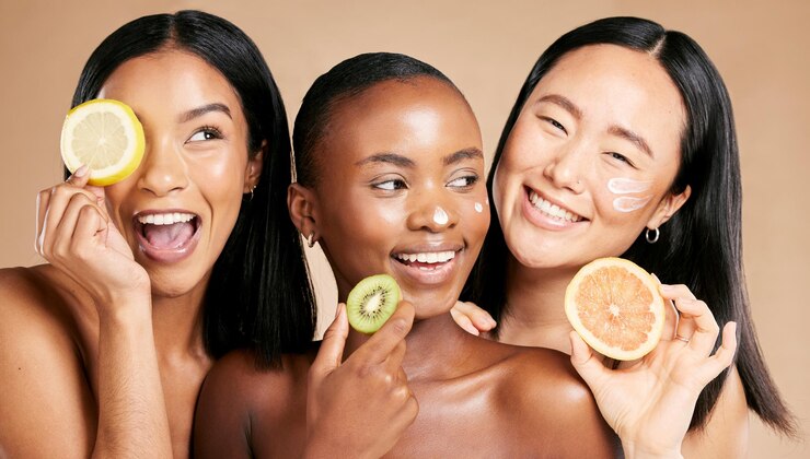 Photo face fruits and women in portrait with cream for facial care beauty and natural cosmetics isolated on studio background sunscreen vegan and different skin with skincare moisturizer and playful