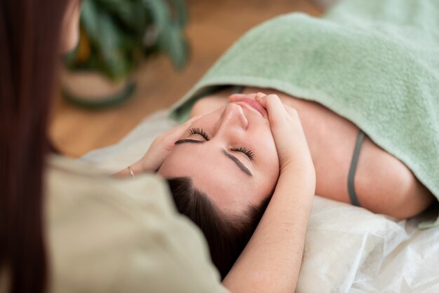 Face of the girl closeup the massage therapist makes massage Green background