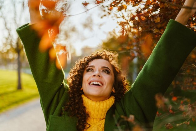 The face of a girl holding up her hand in an autumn park expresses joy and her charming smile bares beautiful white teeth