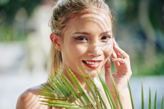 Face of gorgeous young smiling Asian woman talking on phone