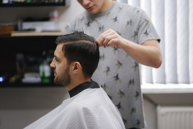 Face of a guy getting a haircut in a hair salon. The hairdresser also wears a mask. The hair has it like the afro