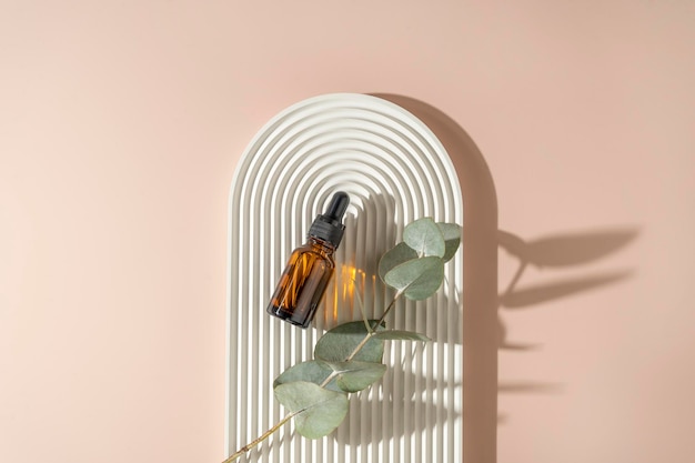 A face or hair serum or essential oil in a brown dropper bottle lying on a white ceramic plate Product marketing cosmetics mockup