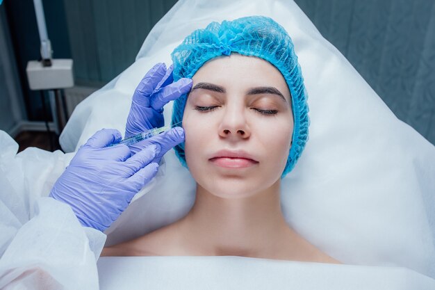 face and hand in glove with syringe making injection