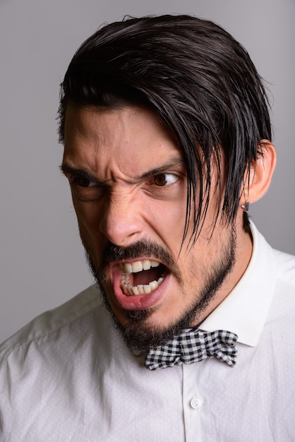 Face of handsome man looking furious against gray background