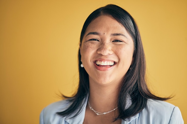 黄色の背景のモックアップスペースに隔離されたスタジオで、幸せでアジアの女性デザイナーと起業家に直面するポートレート、面白くて創造的な専門労働者の笑いとカンボジアのスタートアップ従業員