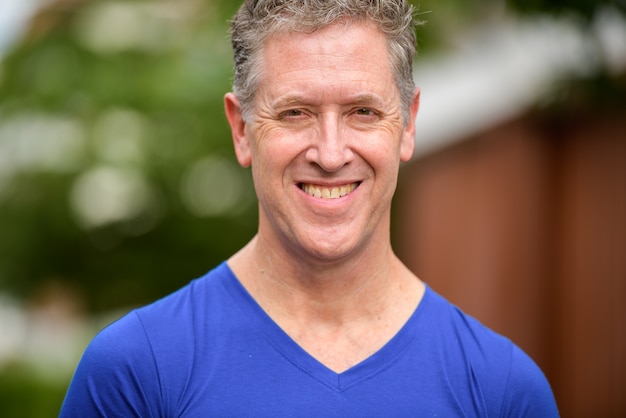 Face of happy mature man smiling in the streets outdoors