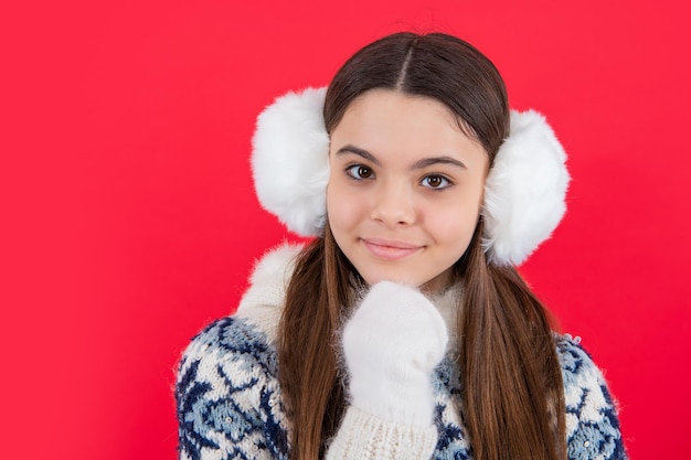 Face of happy teen girl in winter knitwear sweater and headphones in studio teen winter girl