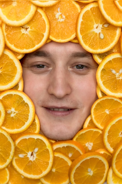 the face of a man in oranges. vitamin C in oranges is a cold medicine. citrus