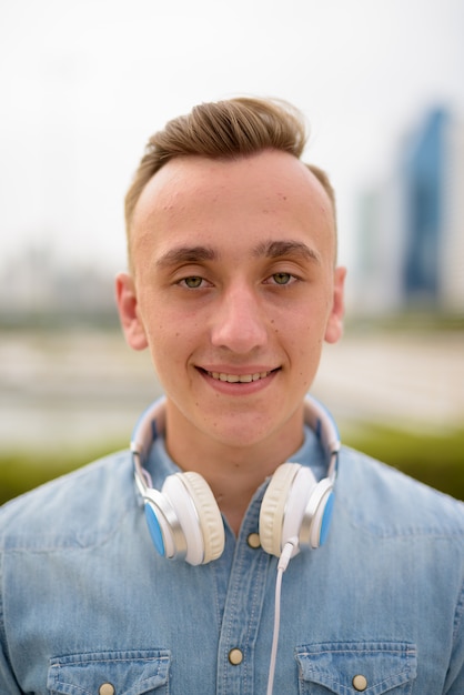 Face of man in park holding headphones
