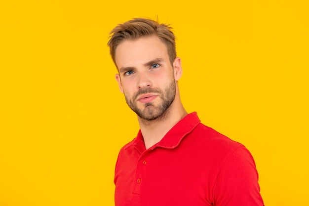 黄色の背景のスキンケアに赤いシャツを着た男の顔