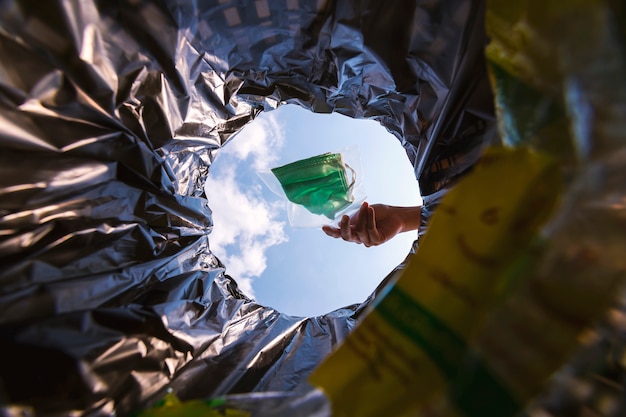 Pacchetto maschera per il viso con chiusura a zip prima di gettarlo nella spazzatura. con una vista a vite senza fine dall'interno del cestino.