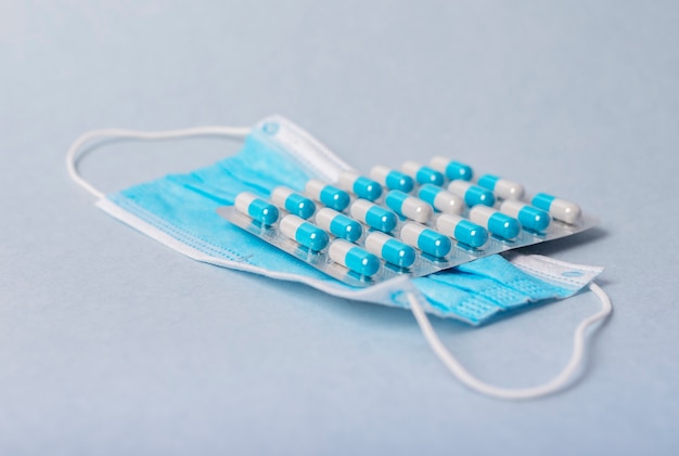 Face mask and pills blister lying on table.