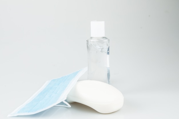 Face mask, soap and hand sanitizer gel isolated in light gray background