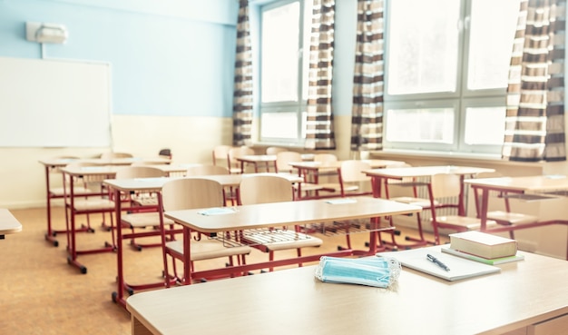 Maschera facciale su un insegnante e un banco di scuola in un'aula scolastica.