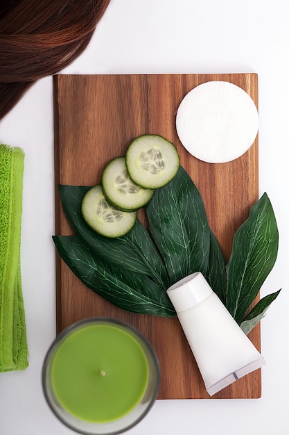 Face mask with cucumber slices, white wood background