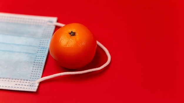 Face mask with tangerine on red background