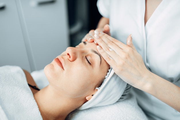 Face massage to female patient, cosmetology clinic