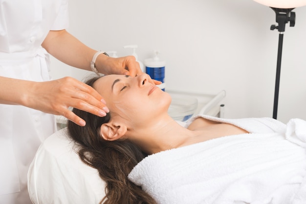 Photo face massage is the favorite part of the week, young woman is relaxing at the cosmetologist.