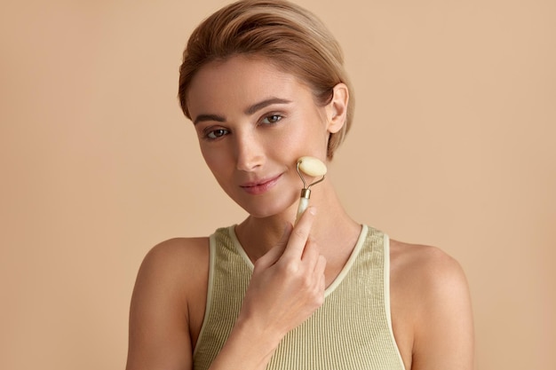 Face massage Smiling Woman Using Jade Facial Roller for Skin Care