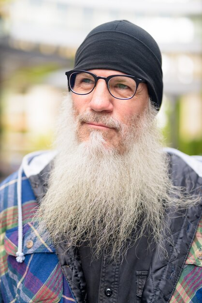 Foto volto di uomo maturo barbuto hipster con occhiali pensando all'aperto