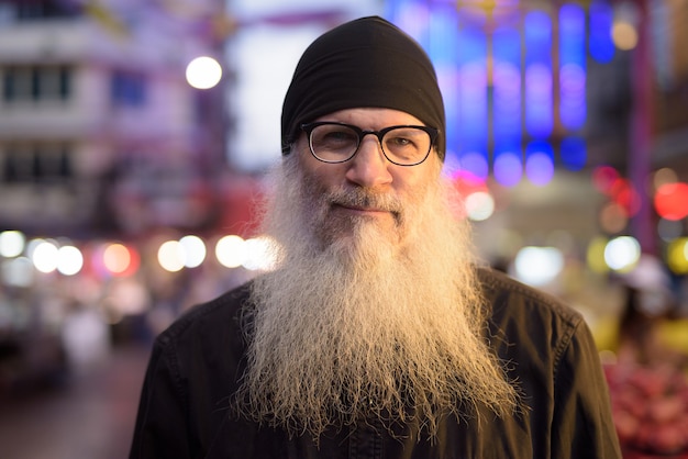 Face of mature bearded tourist man with eyeglasses in Chinatown at night