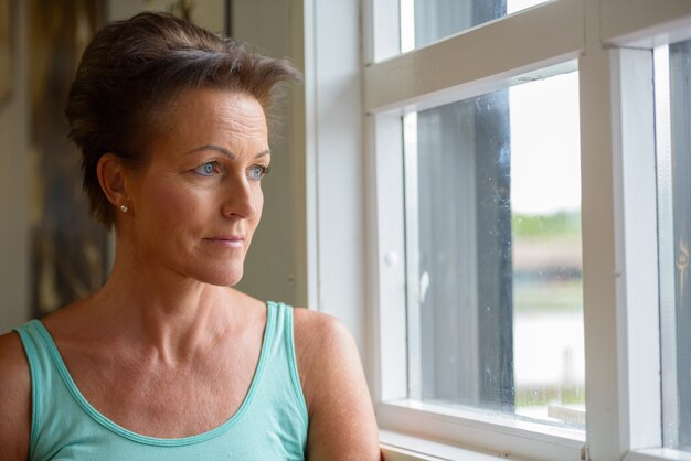 Face of mature beautiful woman looking outside the window