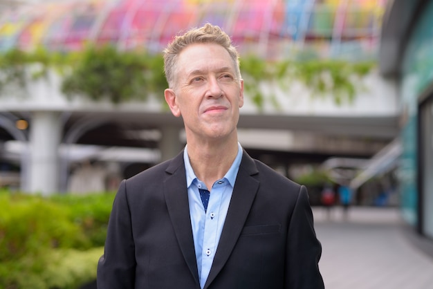 Face of mature businessman in suit thinking outside the building