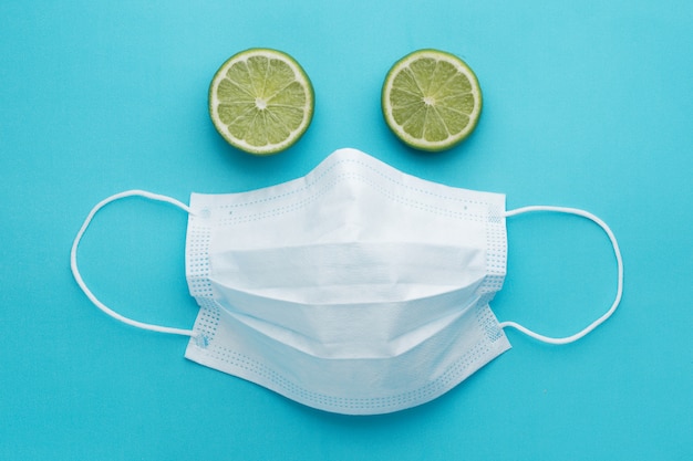 Face of medical mask and green lemon like eyes, blue background.