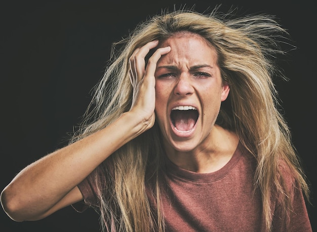 Face mental health and screaming woman headache anxiety or stress Psychology bipolar or crazy insane or depressed schizophrenia female shouting or hearing voices alone on dark studio background