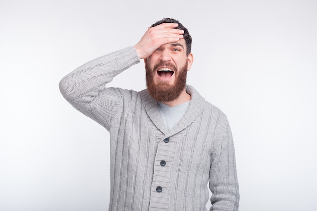 Face palm gesture is made by a young bearded man on white .