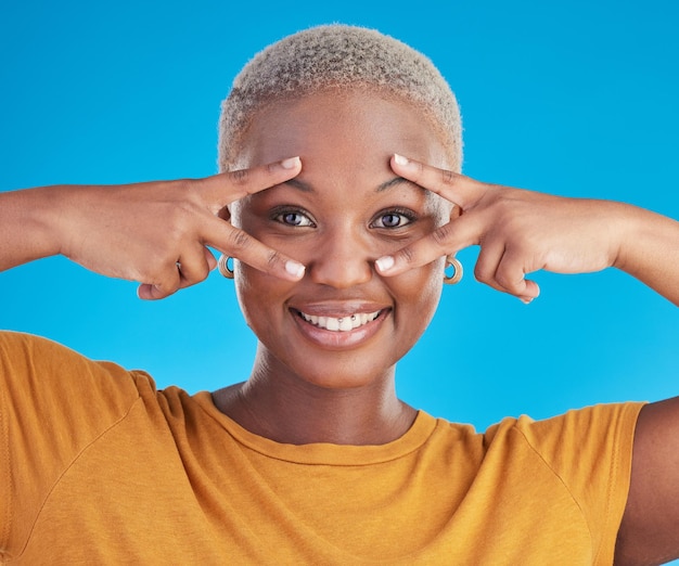 Face peace sign or happy black woman in studio isolated on blue background with smile or confidence Portrait happy gen z girl model or excited African female person with v symbol or hand gesture