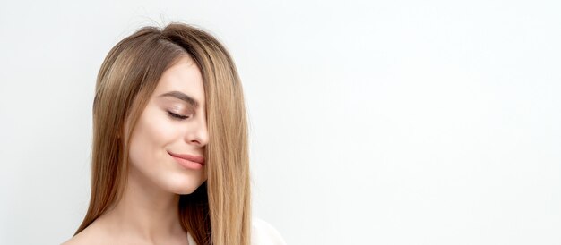 Face portrait of a beautiful young caucasian woman with closed eyes on a white background with copy space