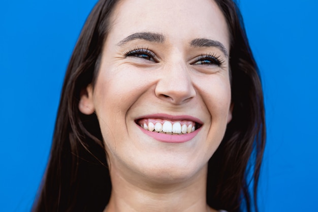 Face portrait of a beautiful young woman smiling with blue