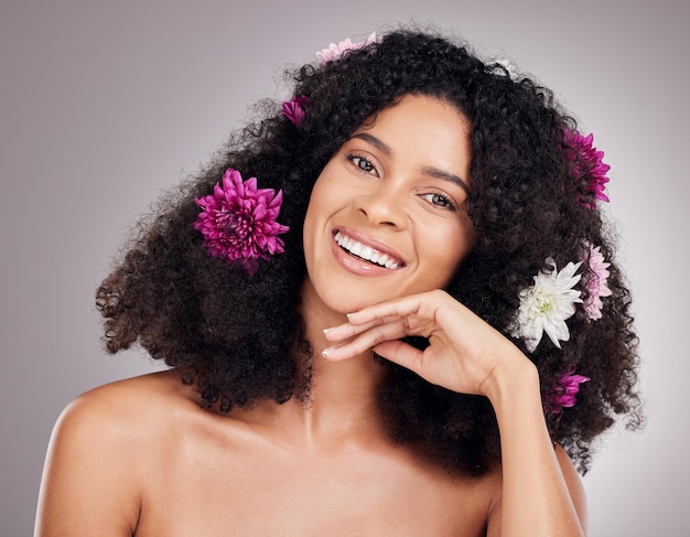 Face portrait hair care flowers and black woman in studio isolated on gray background Floral cosmetics organic makeup and happy female model with flower for hairstyle beauty skincare or wellness