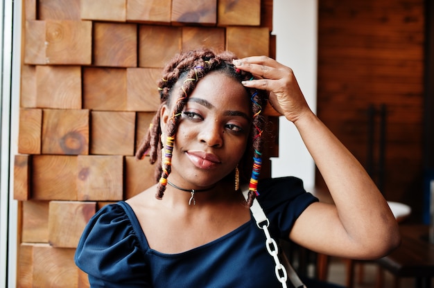 Face portrait of lovely african american woman with dreadlocks at cafe. Beautiful cool fashionable black young girl indoor.