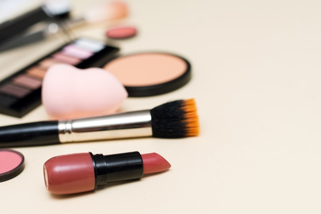 Face powder, brush and various cosmetic decorative makeup products on a color background